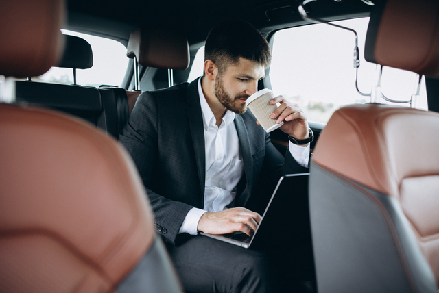 Handsome business man working on a computer in car Handsome business man working on a computer in car